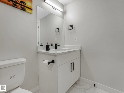 White vanity with a rectangular undermount sink, a white countertop, and a black single-handle faucet - 15731 109 Avenue, Edmonton, AB - Indoor Photo Showing Bathroom