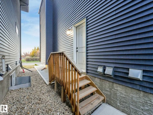 Exterior entry with wood staircase and railing, complemented by blue siding and a concrete foundation - 15731 109 Avenue, Edmonton, AB - Outdoor