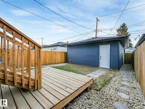 Wood-finish deck with stairs, a privacy fence, a detached structure with horizontal siding and a white entry door, a gravel ground covering, and stepping stones - 15731 109 Avenue, Edmonton, AB - Outdoor With Exterior