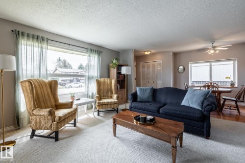 Spacious living area featuring light-colored carpeting, a large picture window, and a built-in ceiling fan with lighting - 3608 16A Avenue, Edmonton, AB - Indoor Photo Showing Living Room