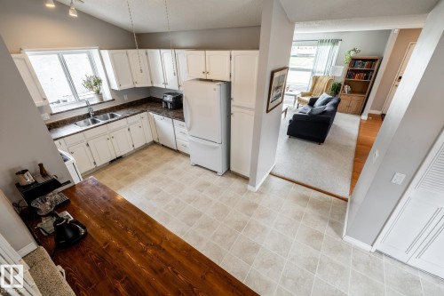 Kitchen as seen from the upper level, featuring white cabinetry, a double basin sink, dark countertops, and light-toned flooring - 3608 16A Avenue, Edmonton, AB - Indoor Photo Showing Kitchen With Double Sink