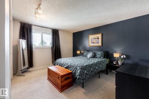 Bedroom featuring a neutral carpet, a dark accent wall, and a double window with dark drapery - 3608 16A Avenue, Edmonton, AB - Indoor Photo Showing Bedroom