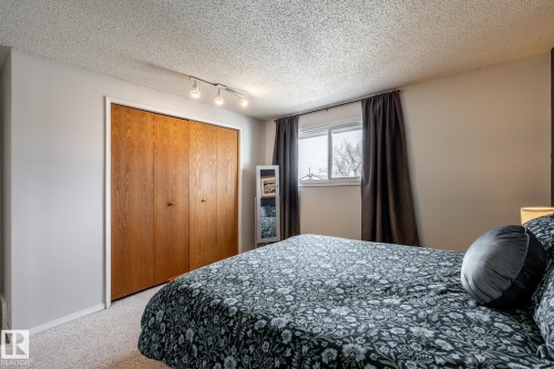 Spacious room featuring wood-finish bi-fold closet doors, track lighting, light-colored carpeting, and a window with white trim - 3608 16A Avenue, Edmonton, AB - Indoor Photo Showing Bedroom