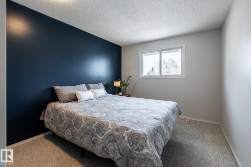 Carpeted bedroom featuring a white-framed window, a dark accent wall, and light-colored walls - 3608 16A Avenue, Edmonton, AB - Indoor Photo Showing Bedroom