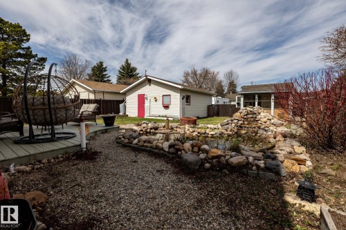 Landscaped backyard featuring a tiered rock water feature, gravel pathways, and a wooden deck - 3608 16A Avenue, Edmonton, AB - Outdoor