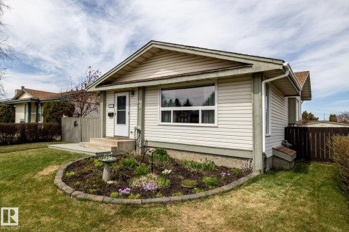 Cream-colored siding home with a brown shingled roof, featuring a front entry door, and a front bay window - 3608 16A Avenue, Edmonton, AB - Outdoor