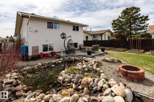 Exceptional landscaped backyard featuring a rock-lined water feature stocked with fish, a brick fire pit, and a patio - 3608 16A Avenue, Edmonton, AB - Outdoor With Exterior