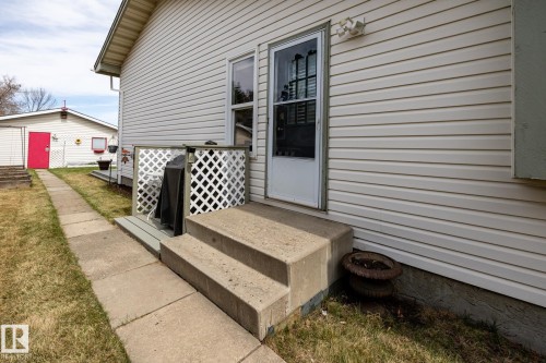 Cream-colored vinyl siding exterior with concrete steps and a storm door entry - 3608 16A Avenue, Edmonton, AB - Outdoor With Exterior