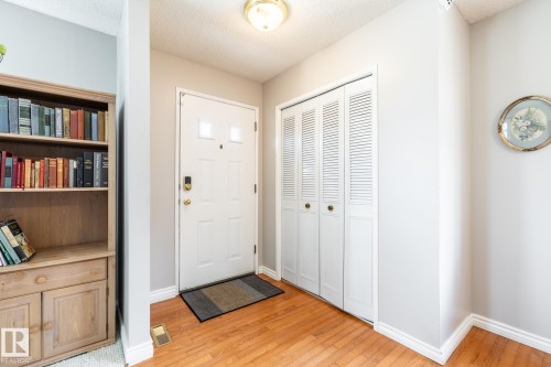 Entryway featuring wood-finish flooring, a white paneled door with decorative glass inserts, and a bifold louvered closet - 3608 16A Avenue, Edmonton, AB - Indoor Photo Showing Other Room