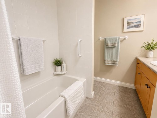 Bathtub with white tile surround and grab bar - 301 9803 96A Street, Edmonton, AB - Indoor Photo Showing Bathroom