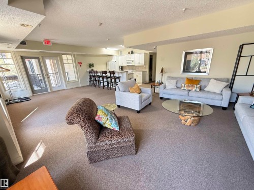 Spacious common area featuring neutral carpet flooring, recessed lighting, and multiple windows with balcony access - 301 9803 96A Street, Edmonton, AB - Indoor Photo Showing Living Room