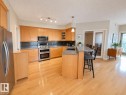 Kitchen featuring wood cabinetry, stainless steel appliances, a black subway tile backsplash, and light wood-finish flooring - 301 9803 96A Street, Edmonton, AB  - Indoor Photo Showing Kitchen 