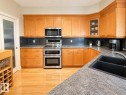 U-shaped kitchen featuring light wood cabinetry, a dark subway tile backsplash, and speckled countertops - 301 9803 96A Street, Edmonton, AB  - Indoor Photo Showing Kitchen With Double Sink 