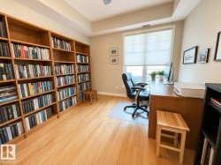 Built-in wood-finish shelving, light wood-finish flooring, and a large window with privacy blinds - 