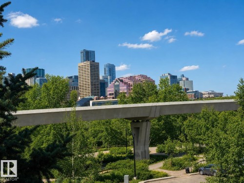 Urban skyline featuring various architectural styles, framed by verdant trees and a clear blue sky - 301 9803 96A Street, Edmonton, AB - Outdoor