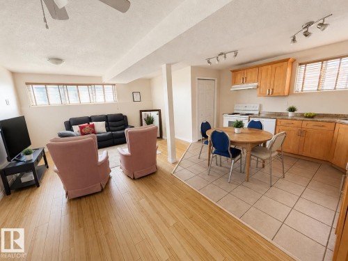 Open-concept living area featuring wood-finish flooring, a ceiling fan, and a kitchen area with light wood cabinetry, a laminate countertop, and tile flooring - 5712 101 Avenue, Edmonton, AB - Indoor