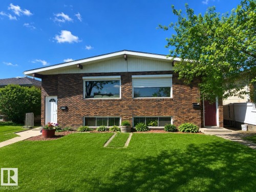 Brick exterior featuring a gabled roofline, white eaves, and a manicured lawn - 5712 101 Avenue, Edmonton, AB - Outdoor