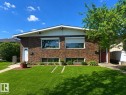 Brick exterior featuring a gabled roofline, white eaves, and a manicured lawn - 5712 101 Avenue, Edmonton, AB  - Outdoor 