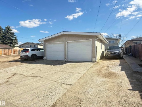 Detached garage featuring two overhead doors, stucco exterior, and a shingled roof - 5712 101 Avenue, Edmonton, AB - Outdoor With Exterior