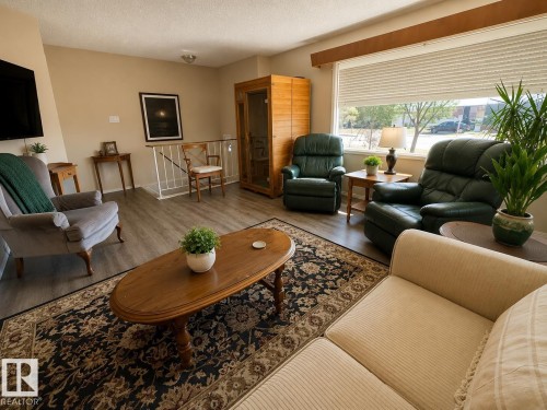 Living space featuring wood-finish flooring, a large window with privacy blinds, and neutral wall tones - 5712 101 Avenue, Edmonton, AB - Indoor Photo Showing Living Room