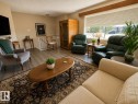 Living space featuring wood-finish flooring, a large window with privacy blinds, and neutral wall tones - 5712 101 Avenue, Edmonton, AB  - Indoor Photo Showing Living Room 