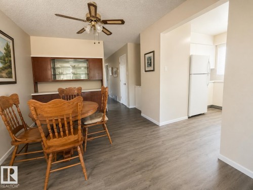 Dining area featuring wood-finish flooring, a built-in wood-toned hutch with glass-front cabinetry, and a ceiling fan with integrated lighting - 5712 101 Avenue, Edmonton, AB - Indoor Photo Showing Dining Room