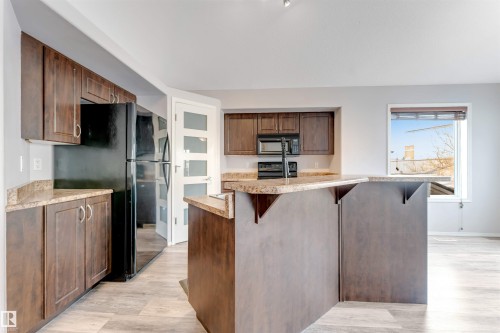 Kitchen island featuring a double-basin sink and integrated dishwasher - 123 Rue Masson, Beaumont, AB - Indoor Photo Showing Kitchen With Double Sink