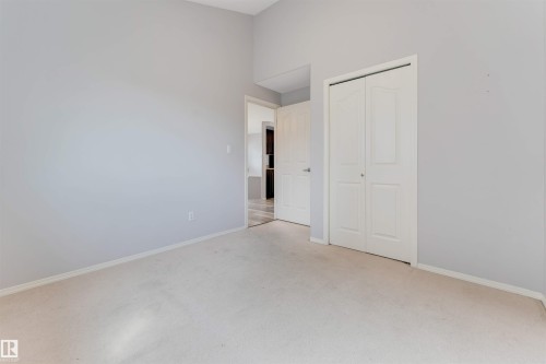 Spacious room featuring vaulted ceilings, wood-finish flooring, a contemporary ceiling fan, and large windows with a backyard fence visible - 123 Rue Masson, Beaumont, AB - Indoor Photo Showing Other Room