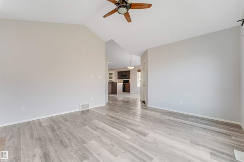 Spacious room featuring vaulted ceilings, a bay window with multiple panes, and neutral carpeting - 123 Rue Masson, Beaumont, AB - Indoor Photo Showing Other Room