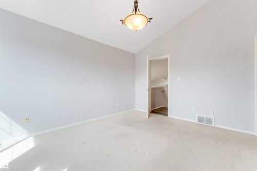 Walk-in closet with neutral-toned walls, white baseboards, light-colored carpeting, built-in shelving, and metal hanging rods - 123 Rue Masson, Beaumont, AB - Indoor With Storage