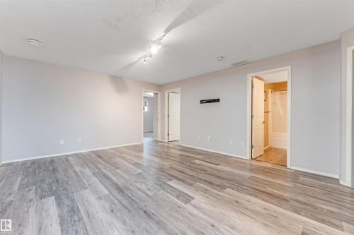 Expansive backyard featuring a partial wood fence, a sloped lawn, and a wooden deck with stairs - 123 Rue Masson, Beaumont, AB - Outdoor