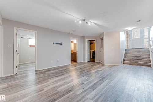 Two-story dwelling featuring a light blue exterior with red trim accents, a front-facing bay window, and a prominent double garage - 123 Rue Masson, Beaumont, AB - Outdoor With Facade