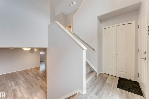 Entryway featuring light wood-finish flooring, a contemporary staircase with white risers and railings, and a double-door closet with panel detailing - 123 Rue Masson, Beaumont, AB - Indoor Photo Showing Other Room