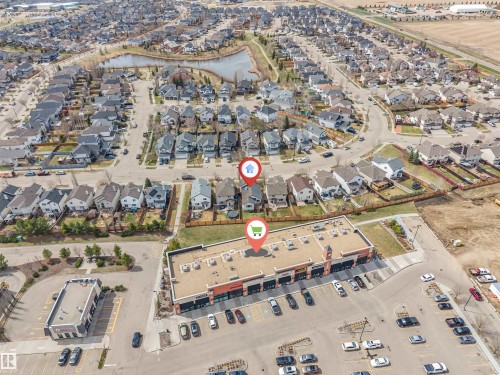 Aerial view showcasing a residential neighborhood with detached homes, developed streets, and surrounding green spaces - 123 Rue Masson, Beaumont, AB - 