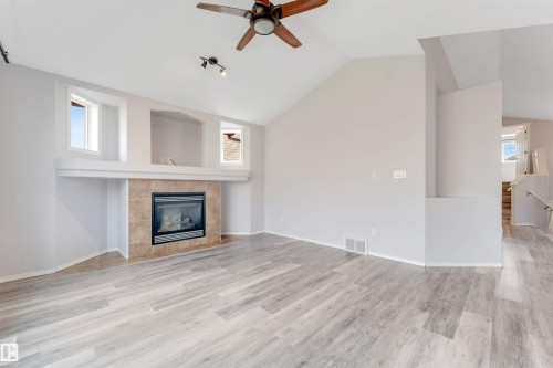 Spacious living area featuring a vaulted ceiling and wood-finish flooring - 123 Rue Masson, Beaumont, AB - Indoor Photo Showing Living Room With Fireplace
