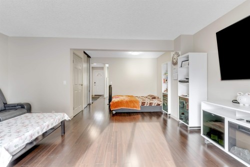 The property features dark hardwood style flooring throughout, light-colored walls, and a white ceiling - 37 1411 Mill Woods Road E, Edmonton, AB - Indoor Photo Showing Bedroom With Fireplace