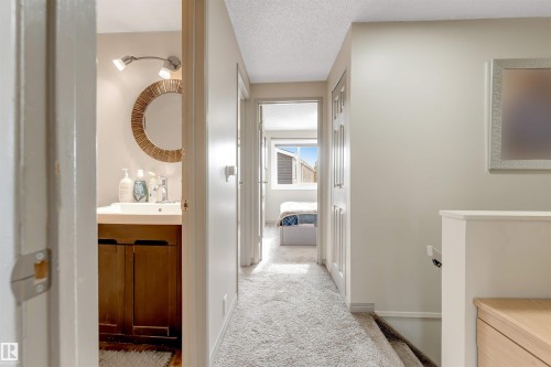 Hallway featuring light-colored carpet flooring and doorways leading to other areas of the property - 37 1411 Mill Woods Road E, Edmonton, AB - Indoor