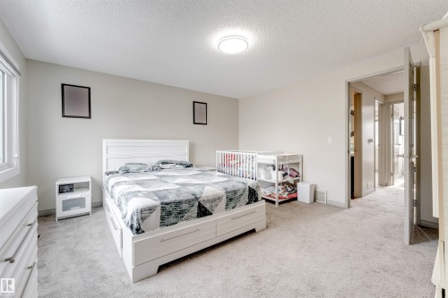 This spacious room features light-colored carpeting, a window providing natural light, and a ceiling-mounted light fixture - 37 1411 Mill Woods Road E, Edmonton, AB - Indoor Photo Showing Bedroom