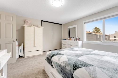 The property features a room with light-colored carpet, a ceiling light fixture, and a window providing natural light - 37 1411 Mill Woods Road E, Edmonton, AB - Indoor Photo Showing Bedroom