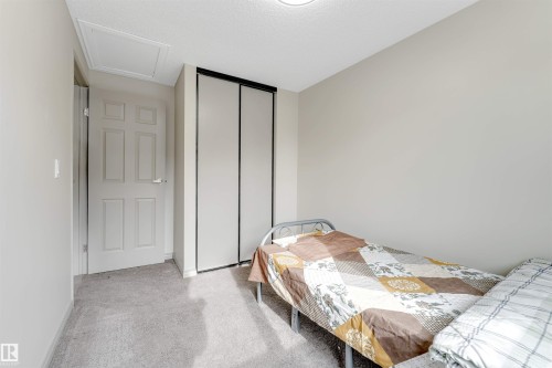 This room features light-colored walls, grey carpet flooring, and a white six-panel door - 37 1411 Mill Woods Road E, Edmonton, AB - Indoor Photo Showing Bedroom