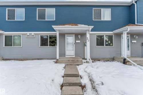 The property features a two-story exterior with blue and gray siding, offering multiple windows and a covered front entryway - 37 1411 Mill Woods Road E, Edmonton, AB - Outdoor