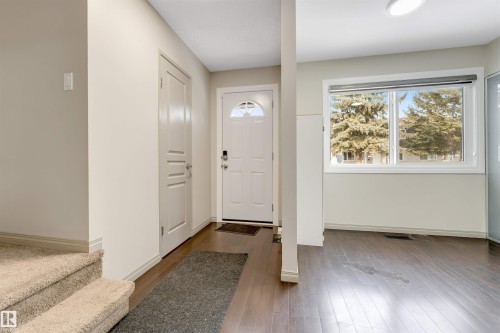 The entry features rich dark wood flooring and a bright white front door with an arched window insert - 37 1411 Mill Woods Road E, Edmonton, AB - Indoor Photo Showing Other Room