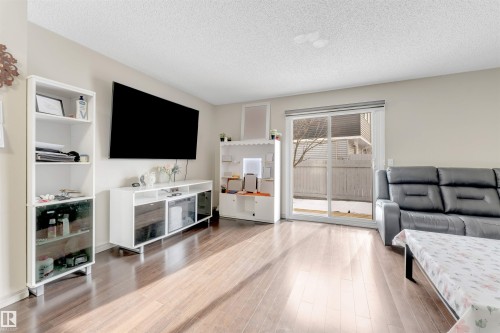 This property features rich hardwood flooring, light-colored walls, and a sliding glass door providing access to the exterior - 37 1411 Mill Woods Road E, Edmonton, AB - Indoor Photo Showing Living Room