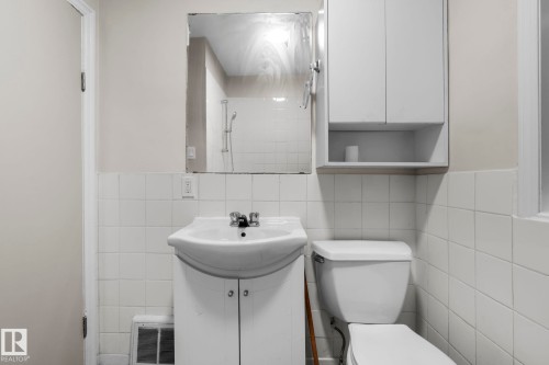 Bathroom featuring a wall-mounted mirror, white pedestal sink with vanity, toilet, and built-in white cabinetry - 11414 85 Street, Edmonton, AB - Indoor Photo Showing Bathroom