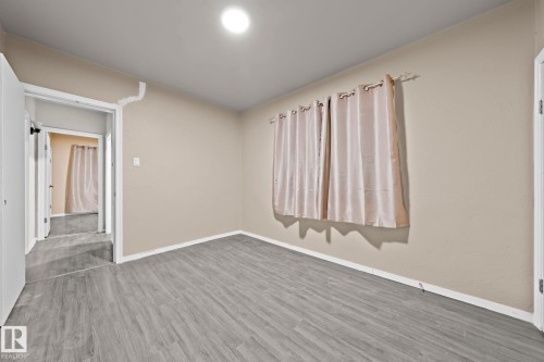 Interior room featuring wood-finish flooring, neutral wall paint, white baseboards, and a flush-mount ceiling light - 11414 85 Street, Edmonton, AB - Indoor Photo Showing Other Room