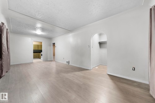 Expansive room featuring wood-finish flooring, light neutral walls, and an arched entry - 11414 85 Street, Edmonton, AB - Indoor Photo Showing Other Room
