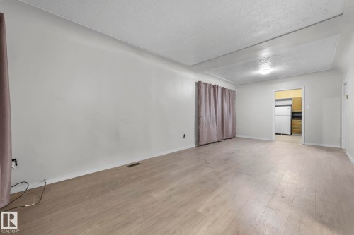 Spacious room featuring light wood-finish flooring, neutral wall tones, and a ceiling light fixture - 11414 85 Street, Edmonton, AB - Indoor Photo Showing Other Room
