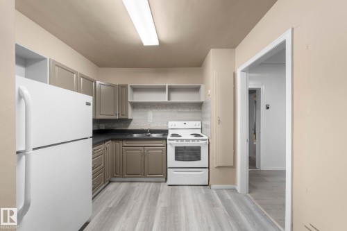 Kitchen featuring gray cabinetry, dark countertops, a mosaic tile backsplash, and wood-finish flooring - 11414 85 Street, Edmonton, AB - Indoor Photo Showing Kitchen