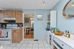 Kitchen featuring light wood cabinetry, white appliances, and a mosaic tile backsplash - 