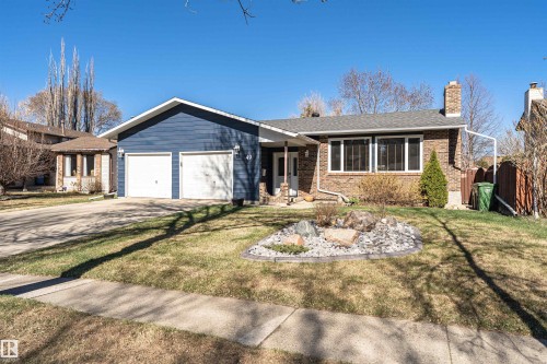 Ranch-style residence featuring a combination of blue siding and brick veneer, an attached two-car garage, a paved driveway, and a front yard with a decorative rock garden - 49 Ash Crescent, St. Albert, AB - Outdoor